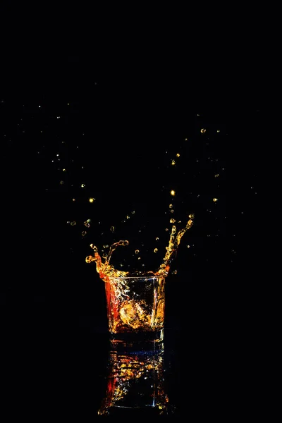 Whisky com respingo sobre fundo preto, conhaque em um copo — Fotografia de Stock