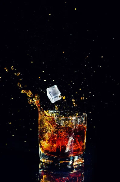 Изолированный выстрел виски с брызгами на черном фоне — стоковое фото