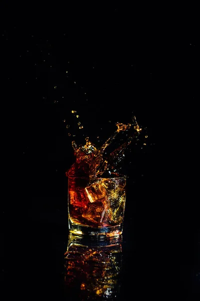 Isolated shot of whiskey with splash on black background — Stock Photo, Image