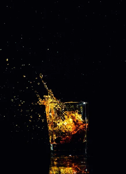 Tiro aislado de whisky con salpicadura sobre fondo negro —  Fotos de Stock