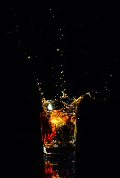 Tiro aislado de whisky con salpicadura sobre fondo negro — Foto de Stock