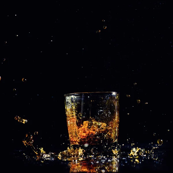 Tiro aislado de whisky con salpicadura sobre fondo negro —  Fotos de Stock
