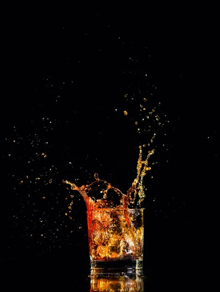 Whiskey met splash op zwarte achtergrond, cognac in een glas — Stockfoto