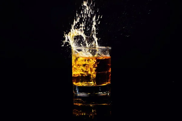 Isolierte Aufnahme von Whisky mit Spritzer auf schwarzem Hintergrund, Brandy — Stockfoto