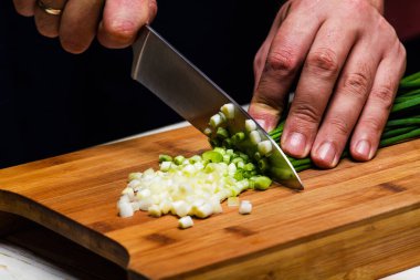 Yemek. Şef mutfakta yeşil soğan kesiyor