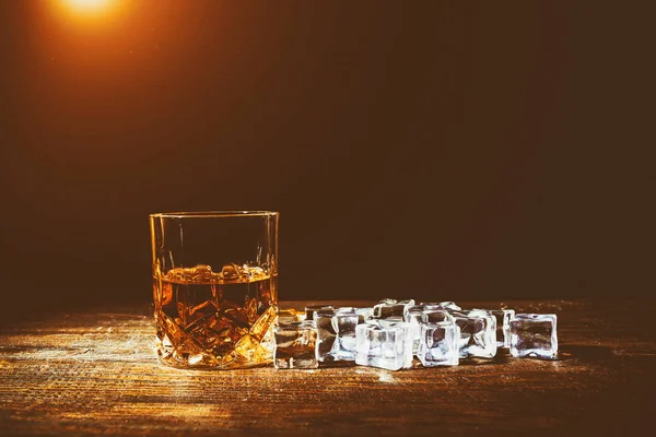 Whiskey with ice cubes on wooden background — Stock Photo, Image