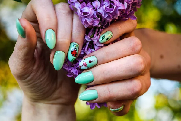 Nails Design. Hands With Bright Green Manicure with flowers. Close Up Of Female Hands. Art Nail.