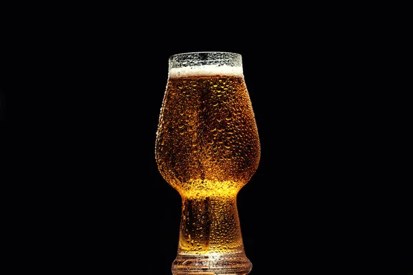 ビールだ 黒い背景の上に木製のテーブルの上に水滴のあるガラスの中の冷たいクラフトライトビール — ストック写真