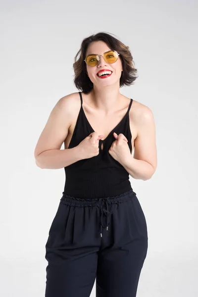 Vacker flicka poserar i en svart T-shirt och glasögon — Stockfoto