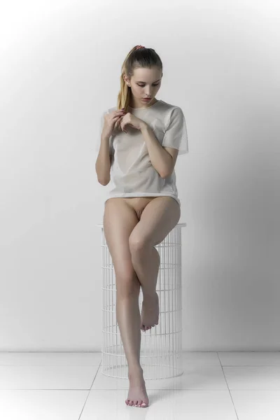 Schönes Mädchen posiert nackt auf einem weißen Stuhl — Stockfoto