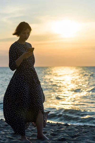 Belle fille avec un téléphone près de la mer — Photo