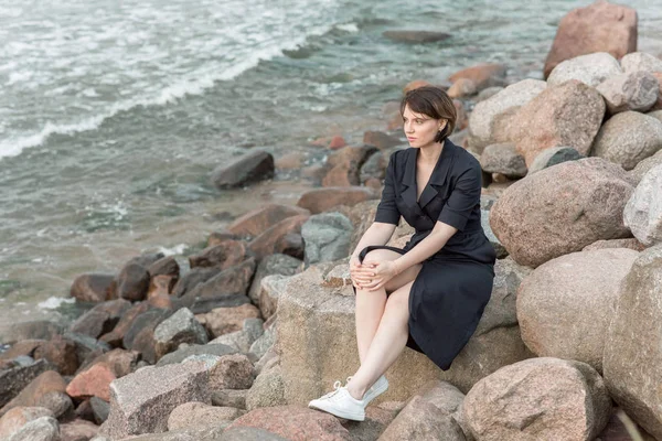 Krásná dívka sedí na skále u moře — Stock fotografie
