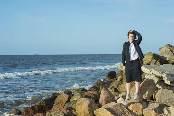 Güzel kız deniz kenarında siyah bir takım elbise poz