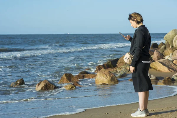 Belle fille posant près de la mer avec un téléphone — Photo