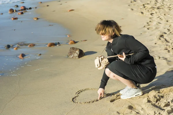 Красивая девушка рисует на песчаном сердце — стоковое фото