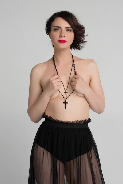 Όμορφη κοπέλα ποζάρει γυμνός με μαύρο σταυρό — Φωτογραφία Αρχείου