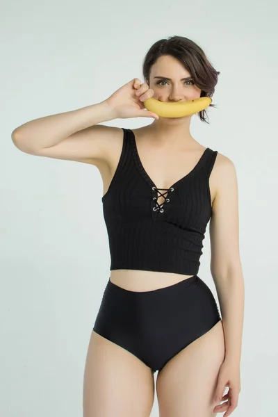 Meisje in een badpak met een banaan — Stockfoto