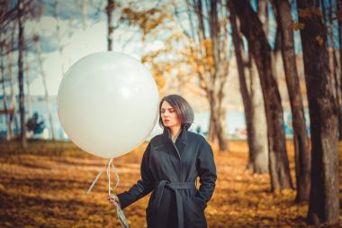  bir sonbahar Park beyaz balon ile siyah paltolu güzel kız