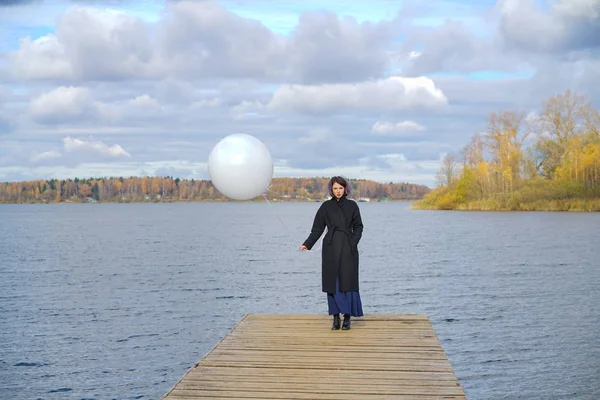 Belle fille posant avec un ballon près de l'eau — Photo