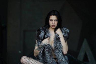 genç güzel kız bir sandalyede oturan bir kürk manto üstsüz poz