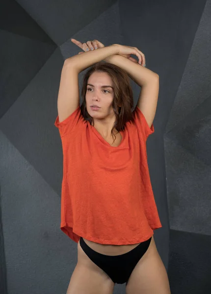 年轻美丽的女孩摆在工作室橙色 T恤衫灰色背景 — 图库照片
