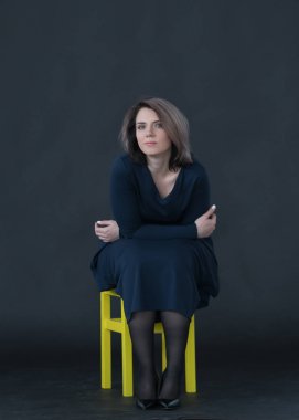 genç güzel kız giydir sandalye üzerinde oturan Studio poz