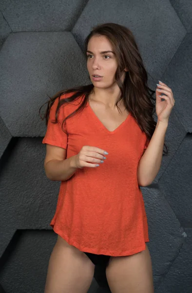 年轻美丽的女孩摆在工作室橙色 T恤衫灰色背景 — 图库照片