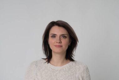 beyaz zemin üzerinde bir stüdyoda bir beyaz kazaklı genç bir güzel kız portresi