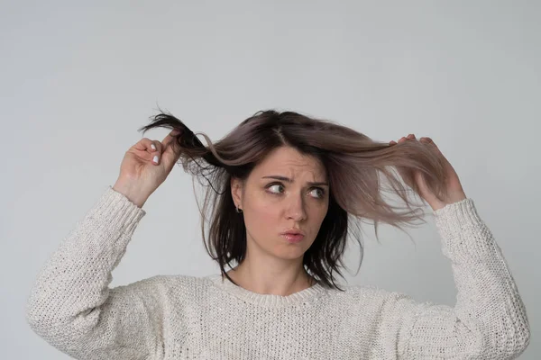 portrait of a young beautiful girl in the studio, holding her hair, bad hair