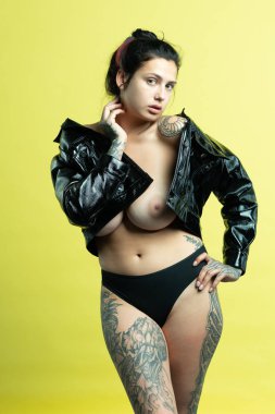 Genç ve güzel bir kız stüdyoda siyah iç çamaşırlarıyla poz veriyor.