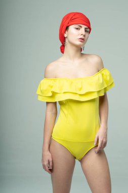 Stüdyoda sarı mayoyla poz veren genç ve güzel bir kız.