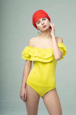 Stüdyoda sarı mayoyla poz veren genç ve güzel bir kız.