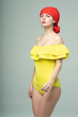 Stüdyoda sarı mayoyla poz veren genç ve güzel bir kız.