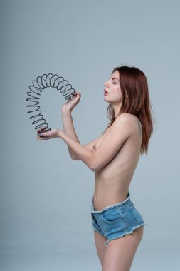 Genç ve güzel bir kız üstsüz poz veriyor, kot pantolonuyla bahar ile duruyor.