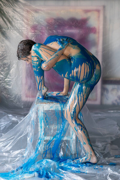 young beautiful woman posing nude, painted with blue paint