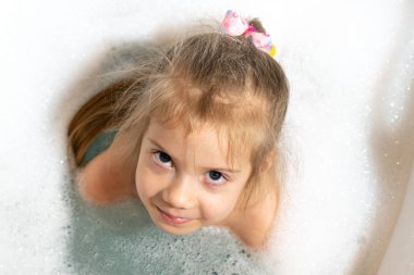 Küçük çocuk banyoda banyo yapıyor.
