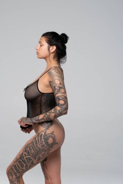 Stüdyoda çıplak poz veren genç ve güzel bir kız. Siyah iç çamaşırlarıyla duruyor.