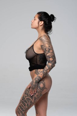 Stüdyoda çıplak poz veren genç ve güzel bir kız. Siyah iç çamaşırlarıyla duruyor.