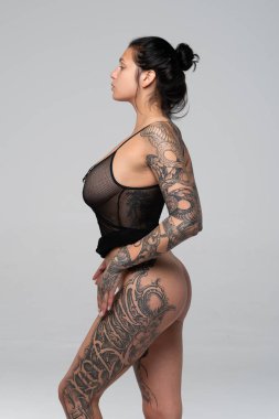 Stüdyoda çıplak poz veren genç ve güzel bir kız. Siyah iç çamaşırlarıyla duruyor.