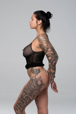 Stüdyoda çıplak poz veren genç ve güzel bir kız. Siyah iç çamaşırlarıyla duruyor.