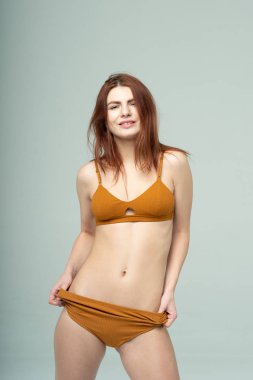 Stüdyoda kahverengi iç çamaşırlarıyla poz veren güzel bir kız.