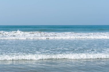 Dalgalar beyaz köpüklü, küçük dalgalı güzel gök mavisi deniz.