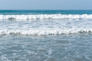 Dalgalar beyaz köpüklü, küçük dalgalı güzel gök mavisi deniz.