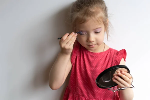 Mała Dziewczynka Maluje Oczy Stoi Czerwonej Sukience — Zdjęcie stockowe