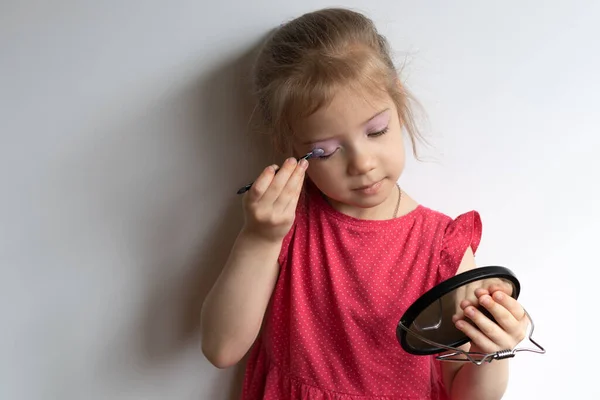 Mała Dziewczynka Maluje Oczy Stoi Czerwonej Sukience — Zdjęcie stockowe