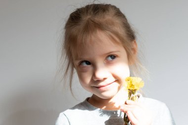 Elinde sarı çiçekler olan küçük bir kızın portresi.