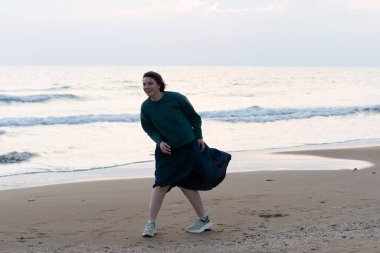 Genç güzel kız sahilde poz veriyor, dans ediyor.