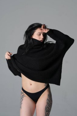 Stüdyoda siyah süveter giyen genç ve güzel bir kadın.