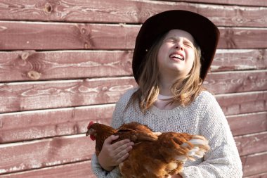 Taşralı kız kollarında tavuk tutuyor.