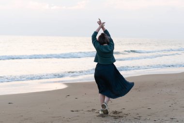 Kız deniz kıyısında kazakla dans ediyor.